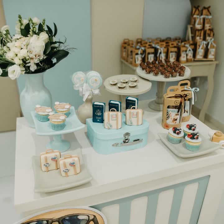 Decoração de festa com tema viajante: passaportes, malinha azul, cupcakes e flores brancas